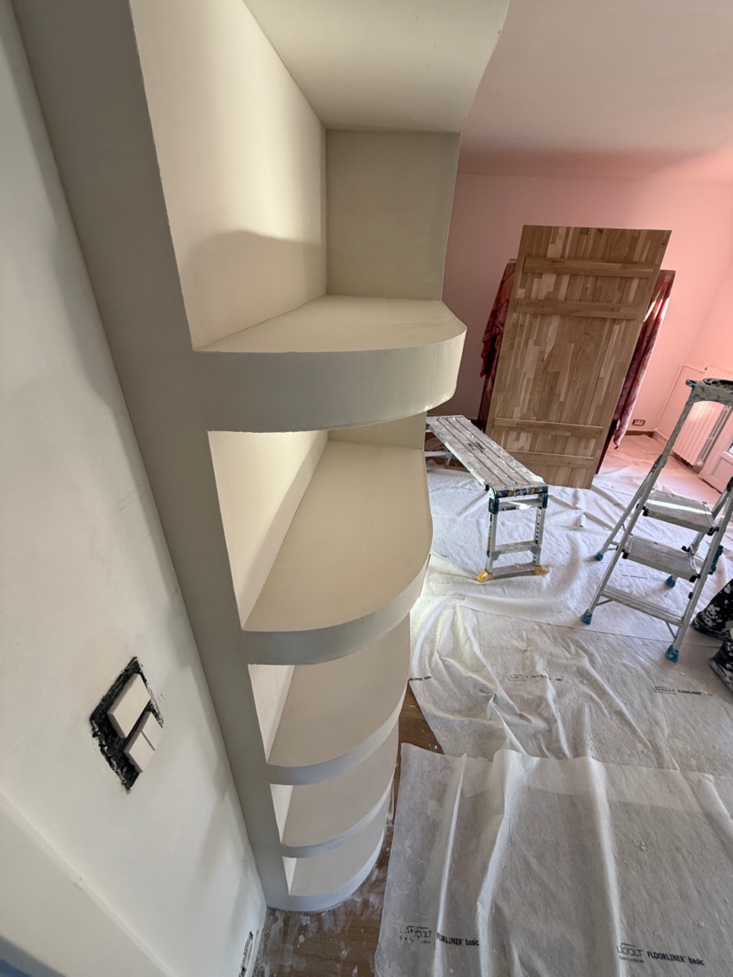 Niches et étagères en placo aux arêtes arrondies, finition blanche sur chantier
